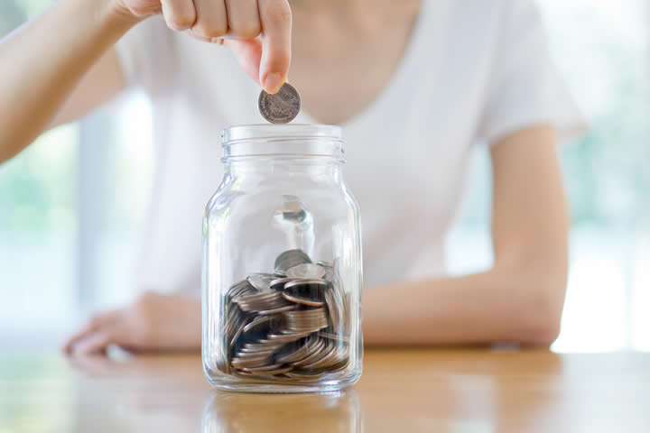 woman putting coins in a jar