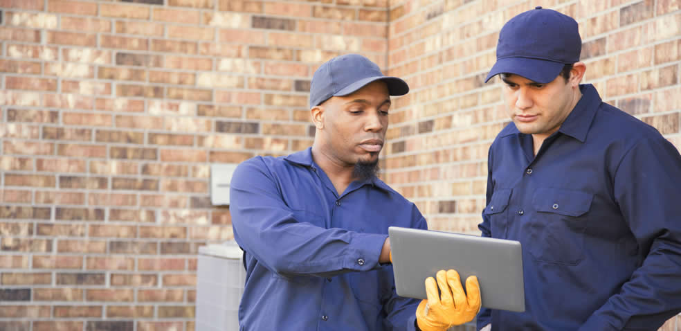 Two Hvac Technicians Looking At Tablet